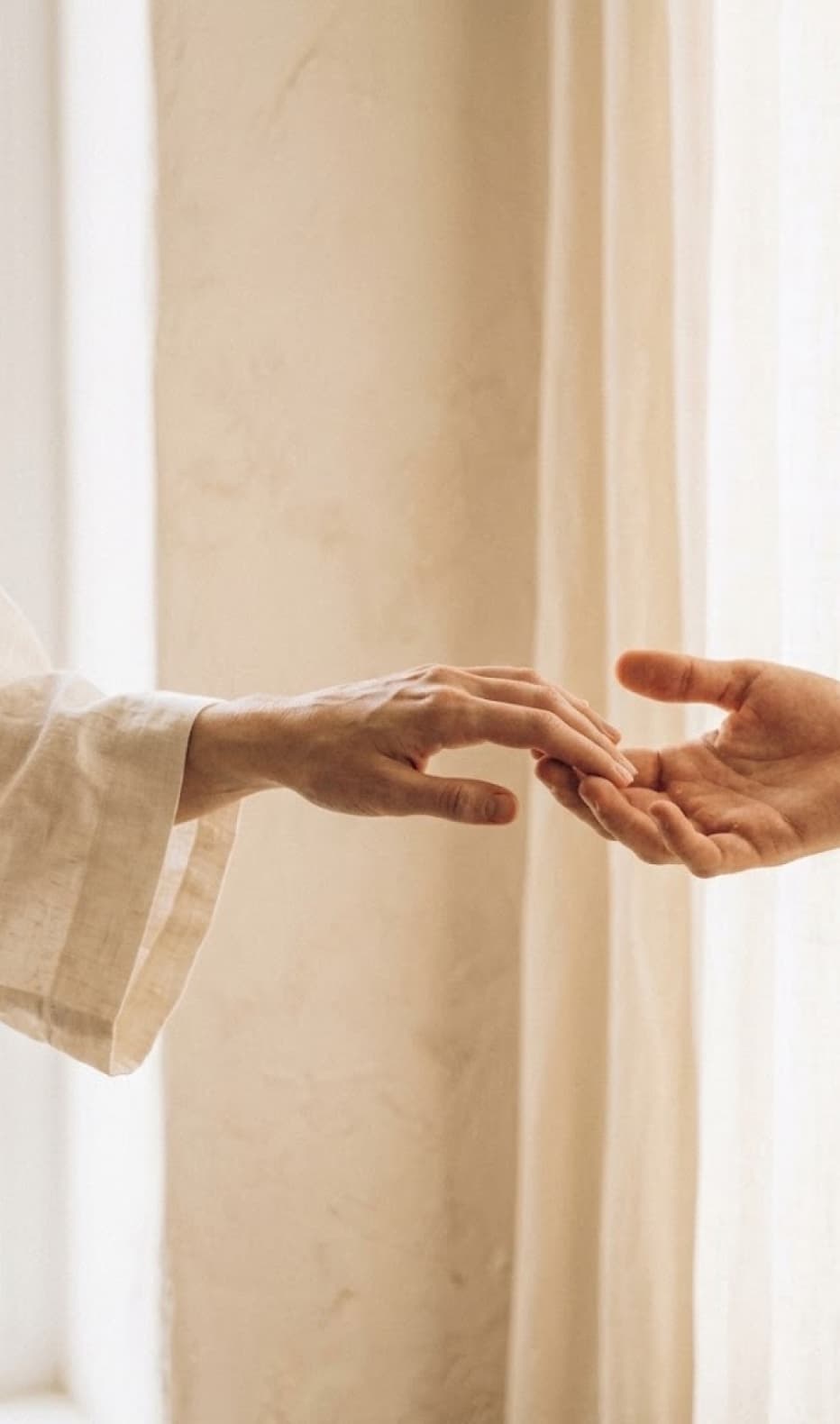 two hands reaching toward each other in soft warm light